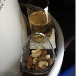 a glass of beer and a bowl of nuts