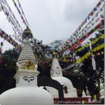 a group of white pagodas with colorful flags