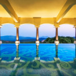 a pool with columns and a view of the mountains