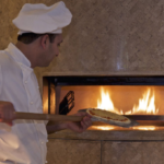 a chef putting pizza on a pizza pan