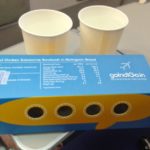 a blue and yellow box with holes and two cups on a table