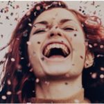 a woman laughing with confetti falling in the air