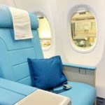 a blue seat with a pillow and a blue pillow in a plane