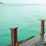 a woman doing yoga on a deck overlooking a body of water