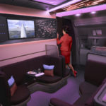 a woman in a red suit standing in a cabin of a plane
