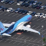 an airplane in a parking lot with cars parked in the background