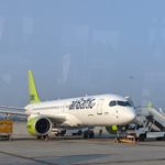 a white airplane with green tail and yellow wheels