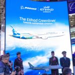 a group of people standing in front of a large sign with an airplane