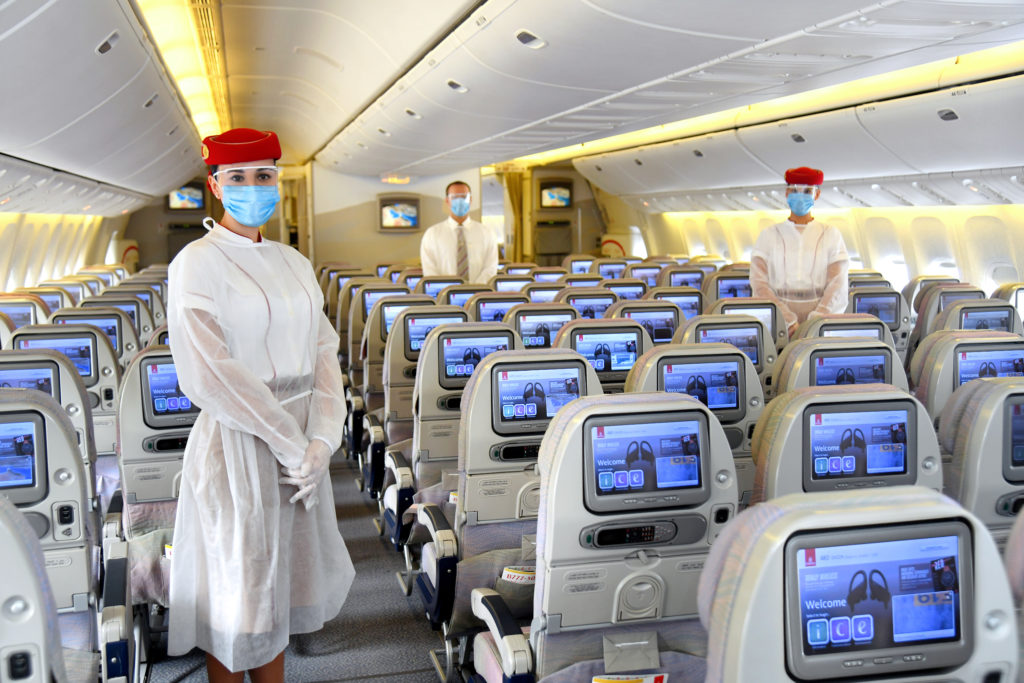 a group of people wearing face masks and standing in an airplane