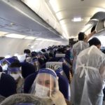 people in a plane with people wearing face masks and plastic
