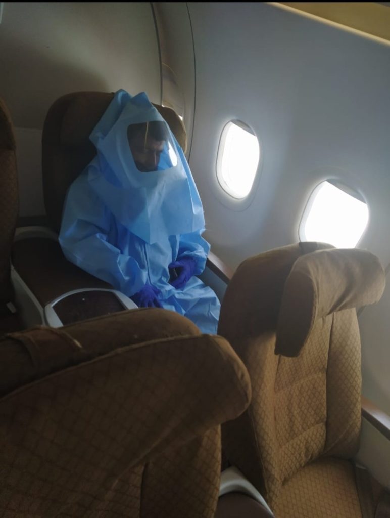 a person in a protective suit sitting in a plane