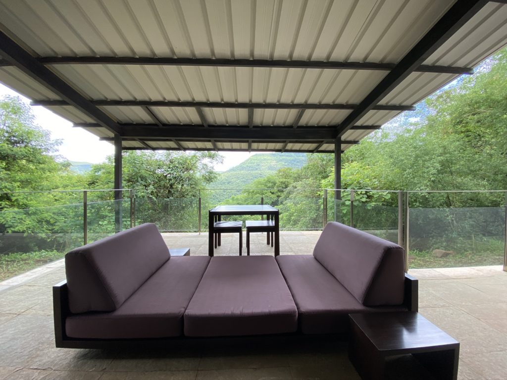a couch and table outside with a roof