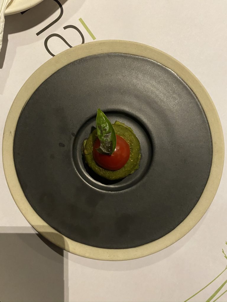 a plate with a tomato and a leaf on it