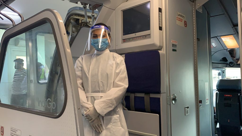 a person in a white coat and face mask standing in a room