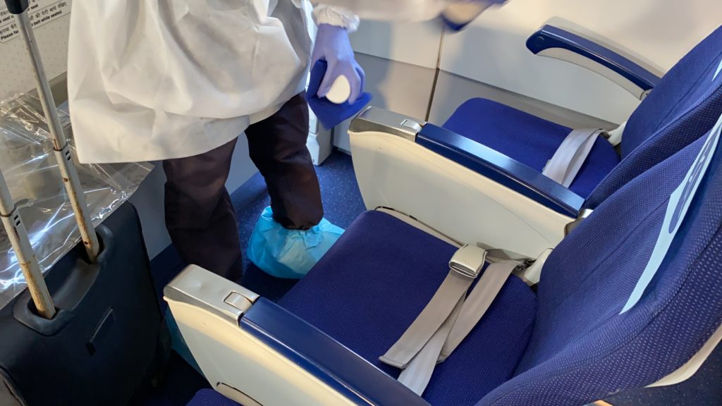 a person in a white coat and gloves cleaning a seat