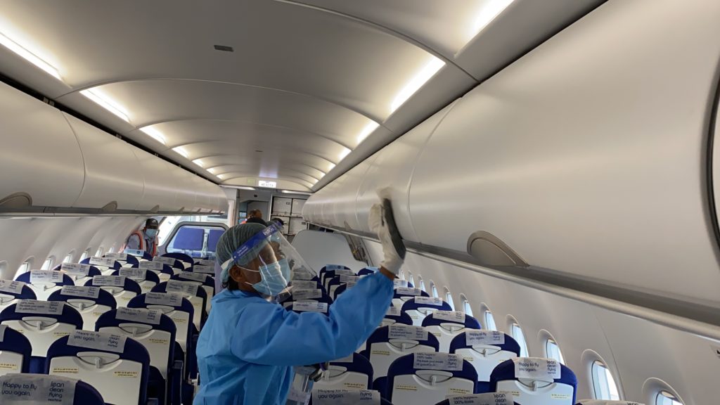 a person wearing a face mask and gloves cleaning an airplane