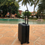 a black suitcase on a stone surface next to a pool