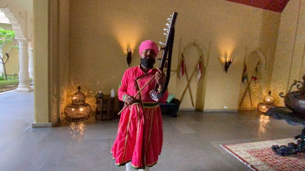a man in a pink turban holding a musical instrument