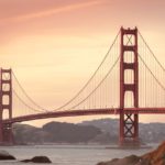 Golden Gate Bridge over water with a pink sky