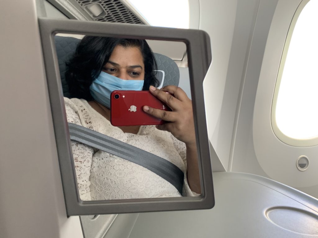 a woman wearing a face mask taking a selfie in a mirror