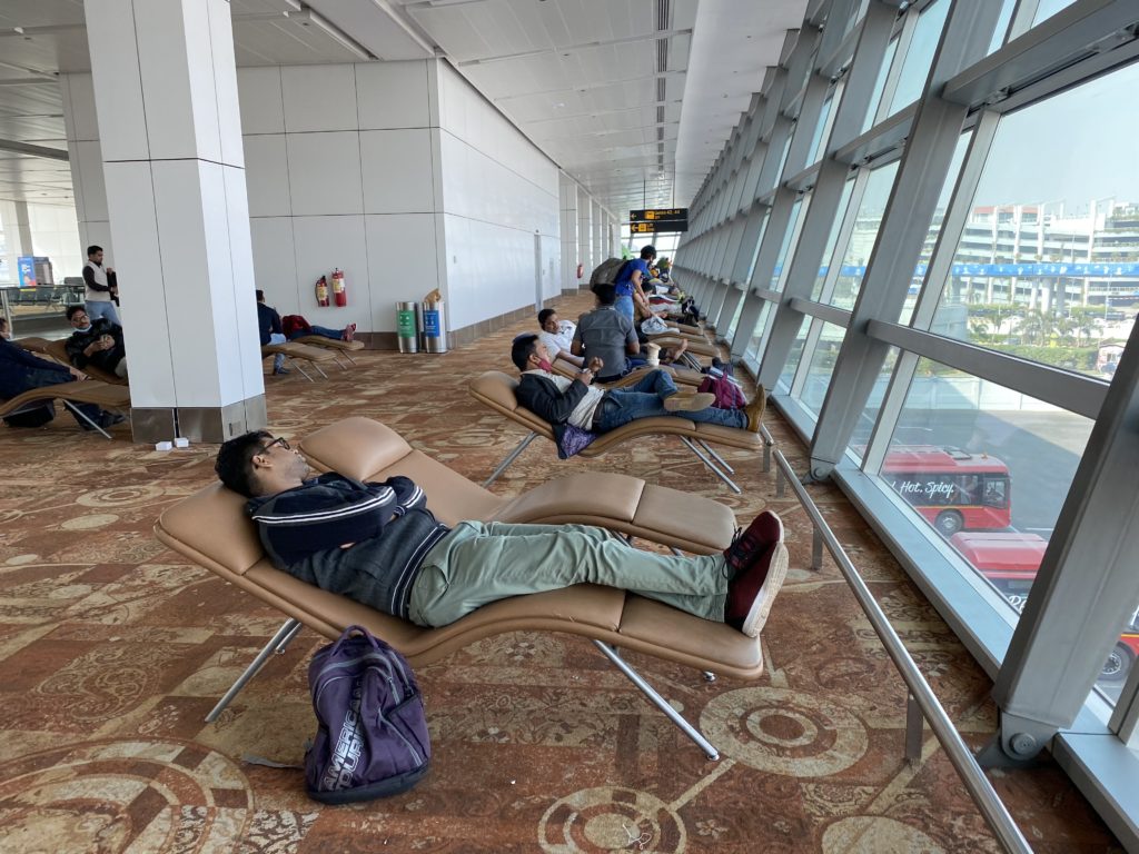 a group of people sleeping in chairs in a terminal