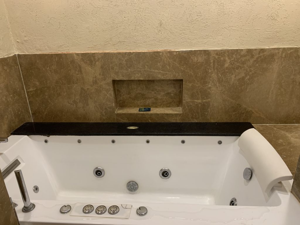 a white bathtub with a brown tile wall