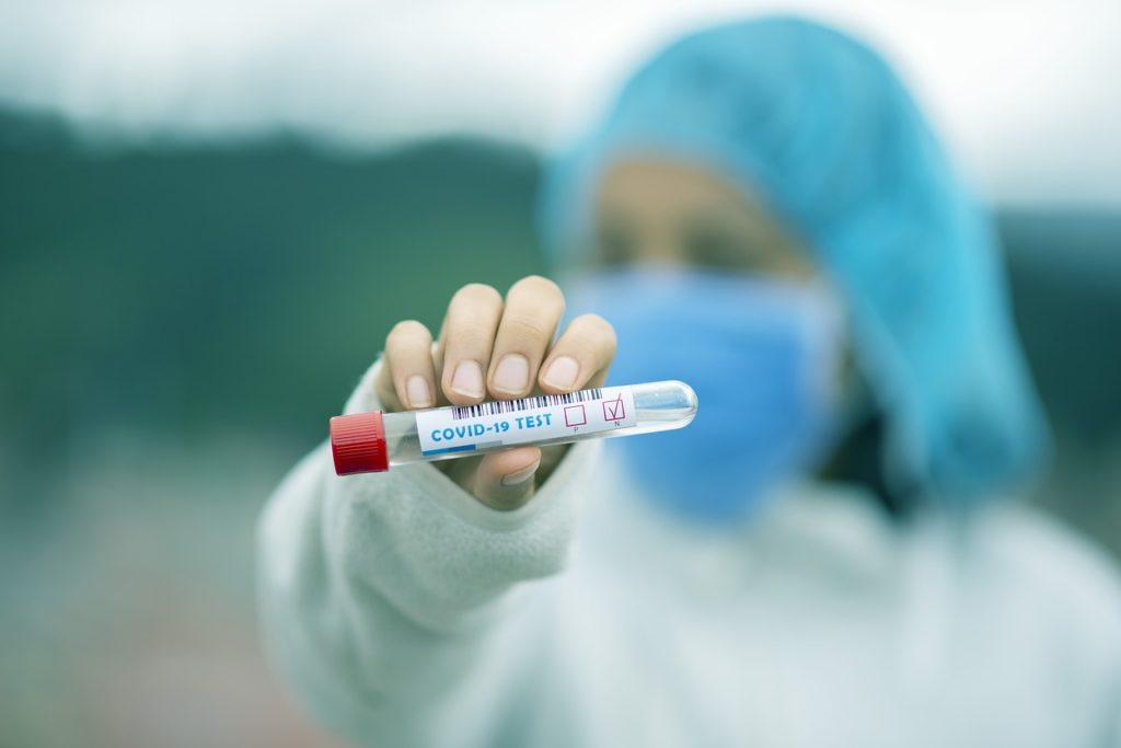 a person wearing a face mask holding a test tube