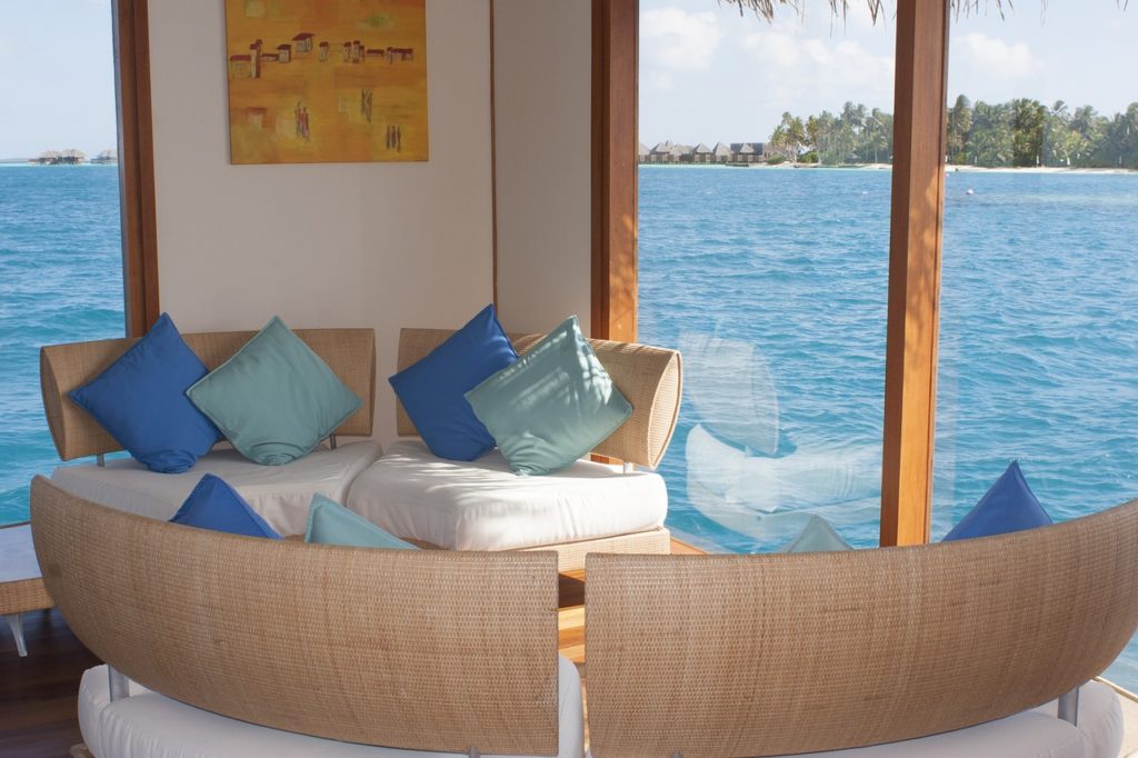 a couch with pillows in a room with a view of the water