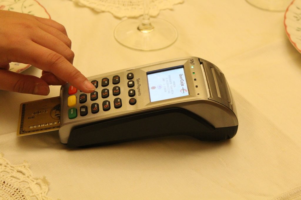 a hand pressing a button on a credit card reader