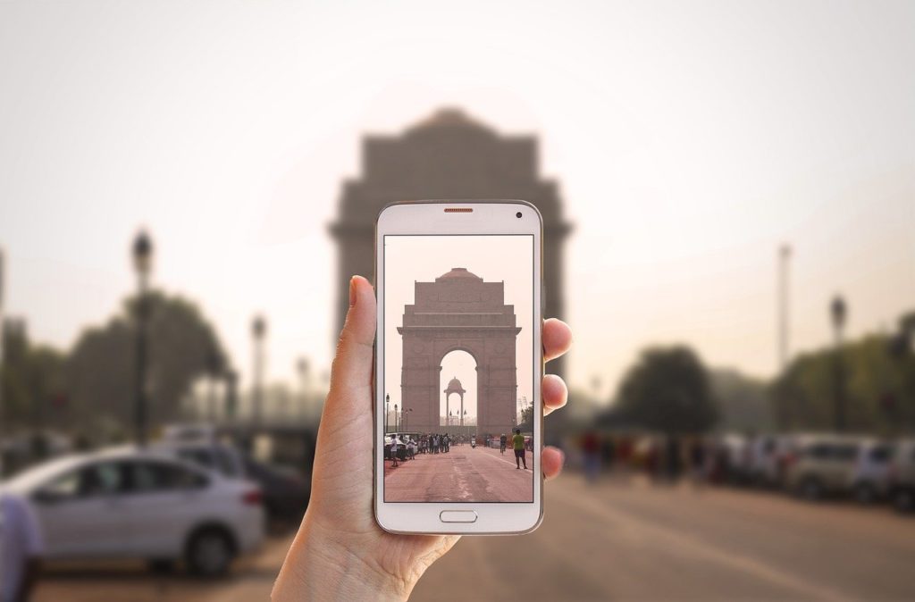 a hand holding a phone with a large archway in the background