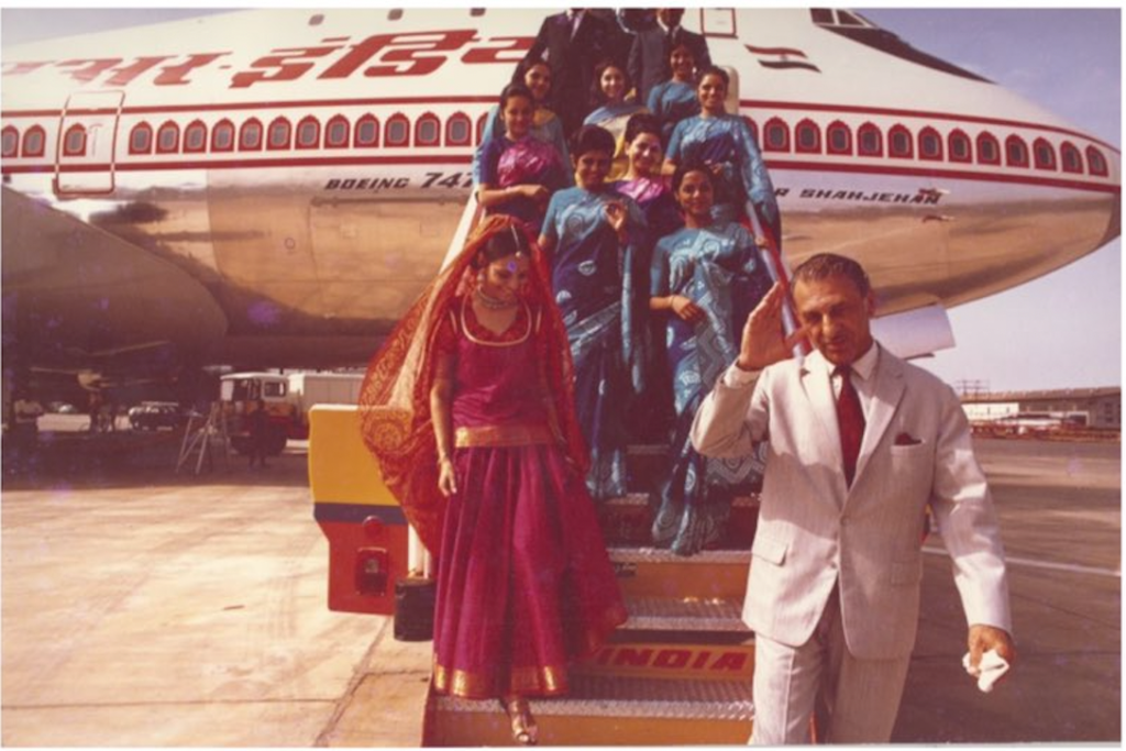 a man in a suit and a woman in a sari standing on a plane