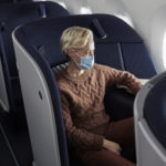 a woman wearing a face mask sitting in an airplane