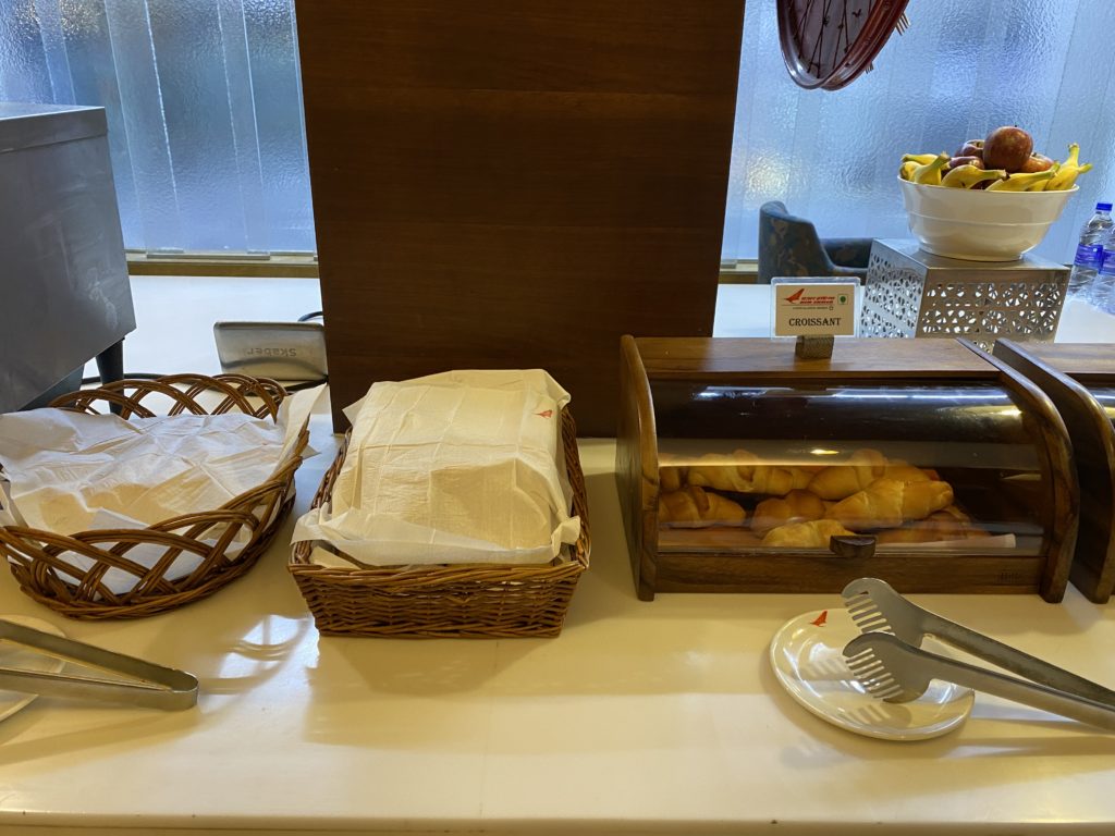 a buffet table with baskets of croissants and a plate of fruit