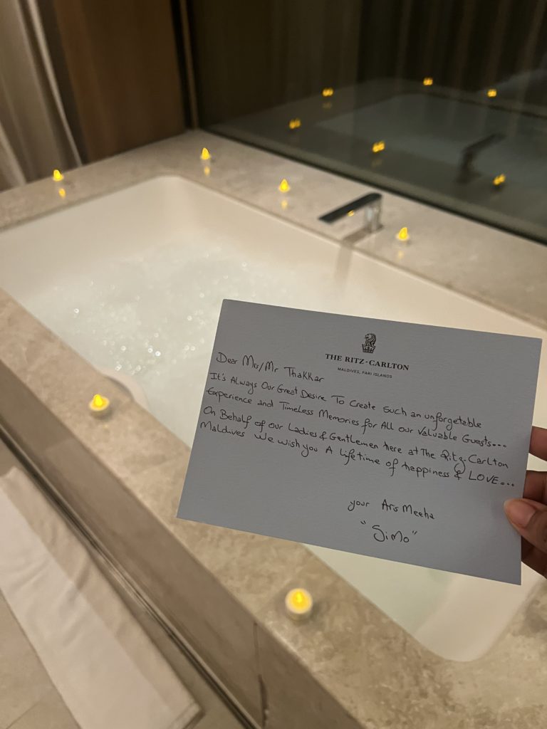 a hand holding a card in front of a bathtub