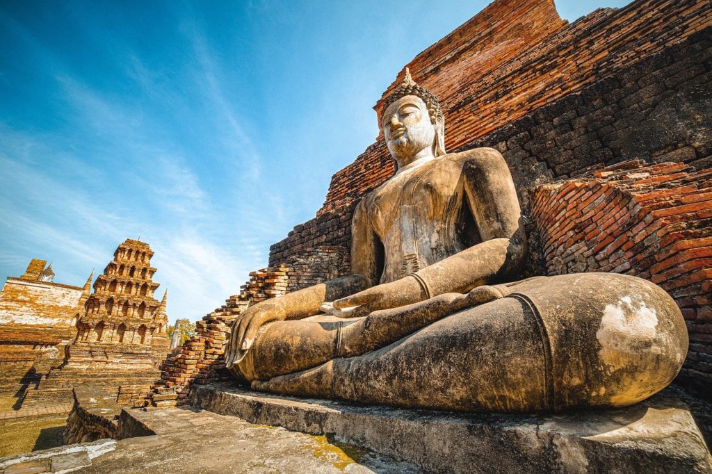 a statue of a buddha sitting in front of a brick wall