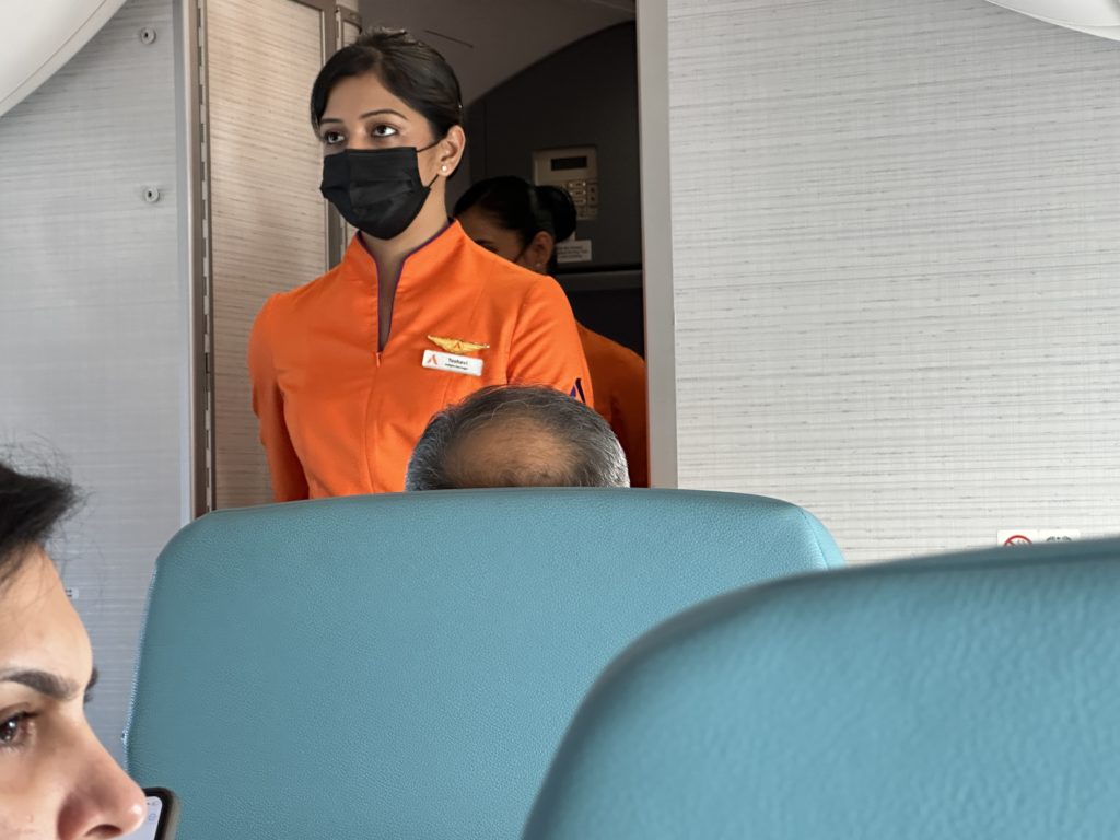 a woman wearing a face mask and standing in an airplane