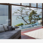 a living room with a view of the ocean and a tree