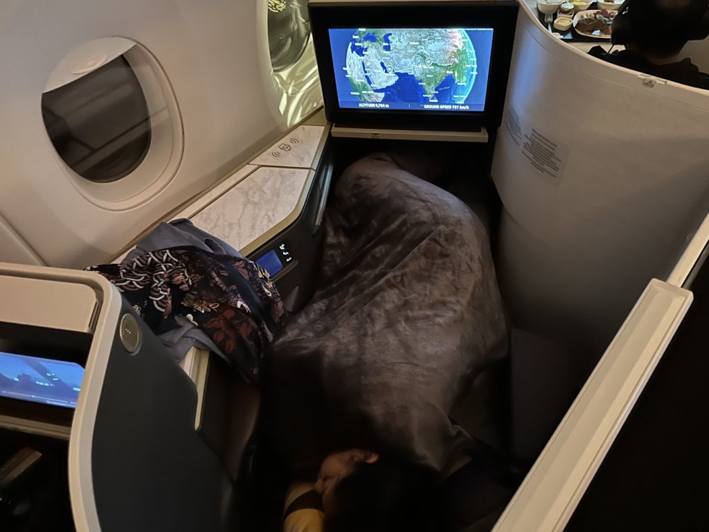 a person sleeping in an airplane with a television