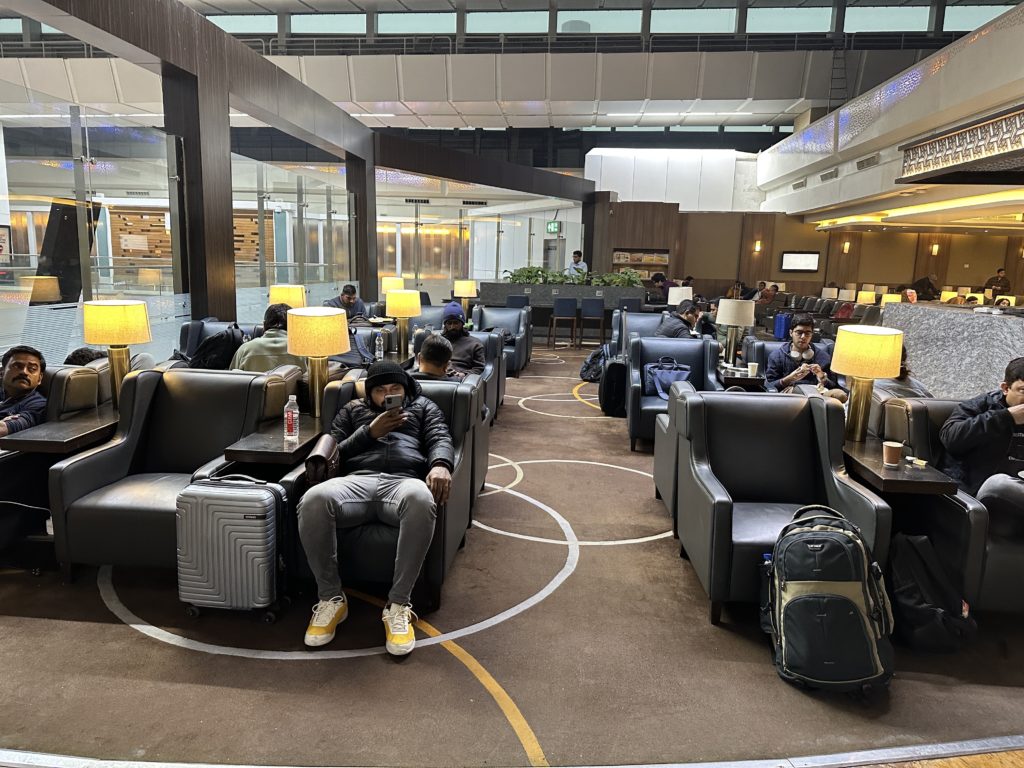 a group of people sitting in a lounge area with chairs and lamps