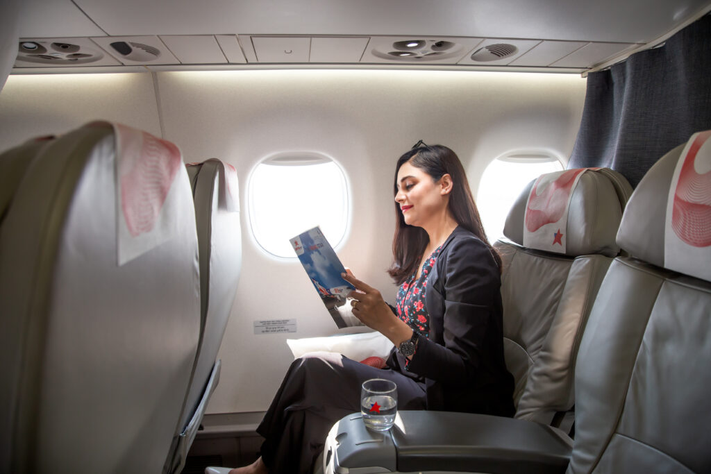 a woman sitting in an airplane reading a magazine