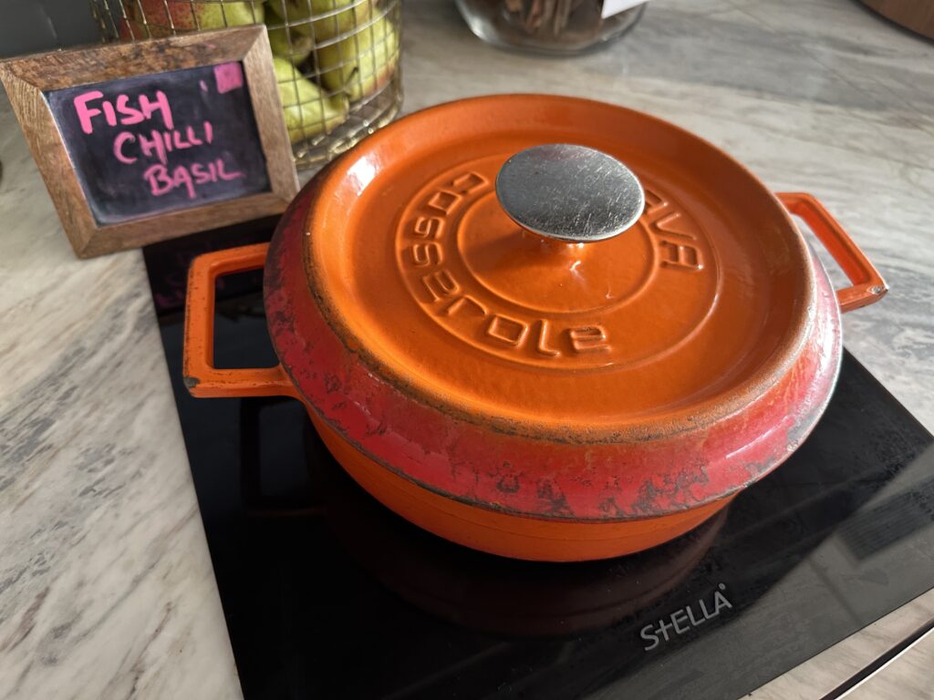 an orange cast iron pot on a black surface