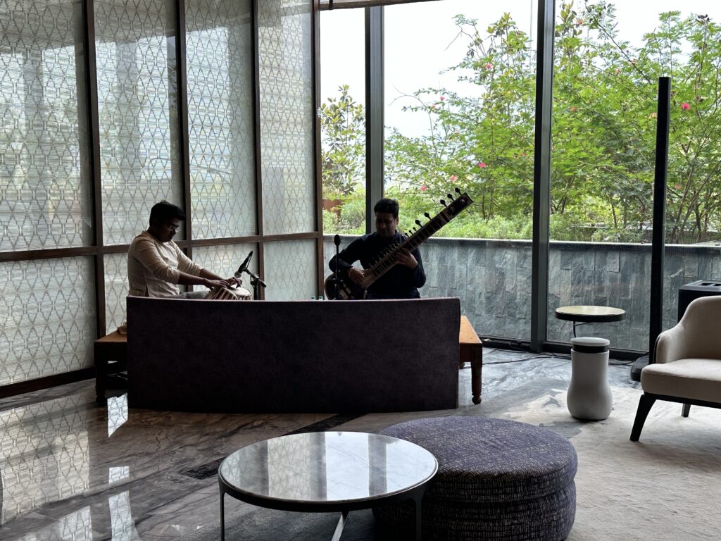 a group of people playing instruments in a room with large windows