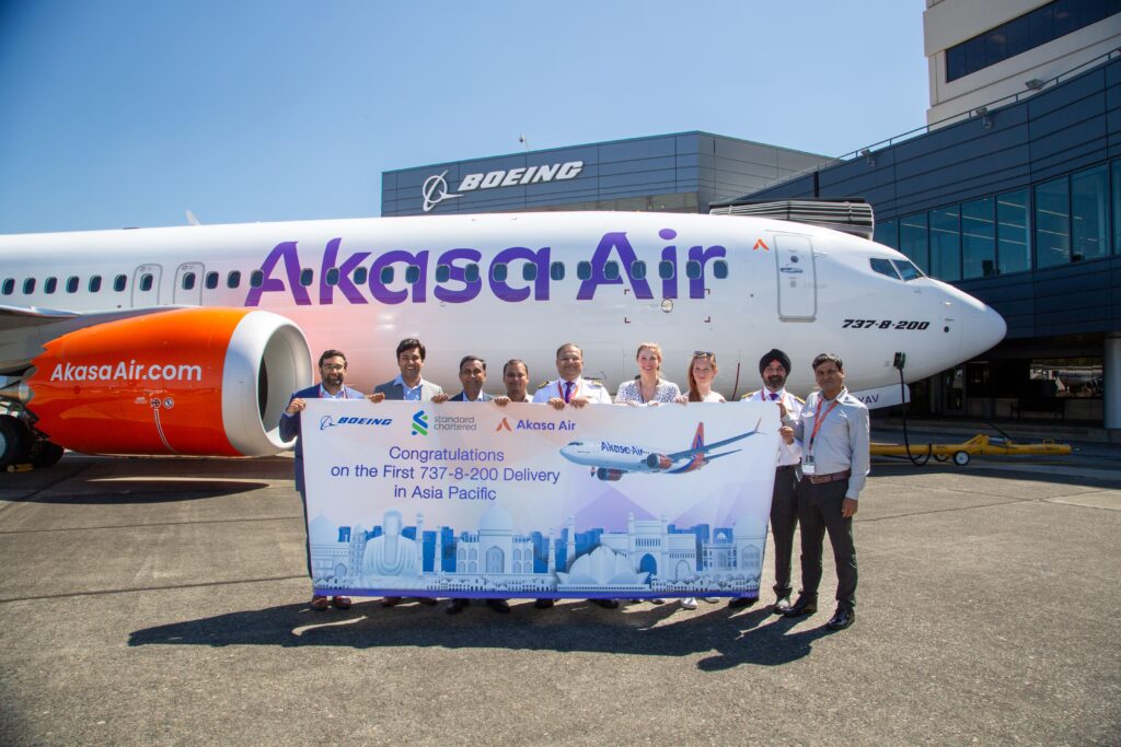 a group of people holding a large banner in front of an airplane