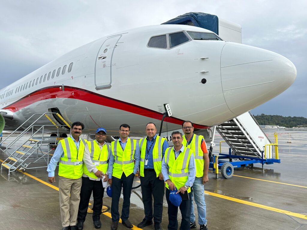 a group of men in reflective vests standing in front of a plane