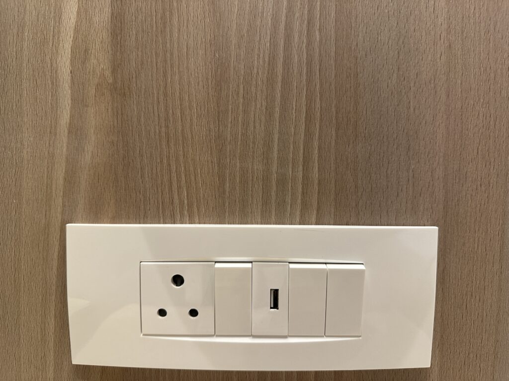 a white light switch with a plug and a socket on a wood surface