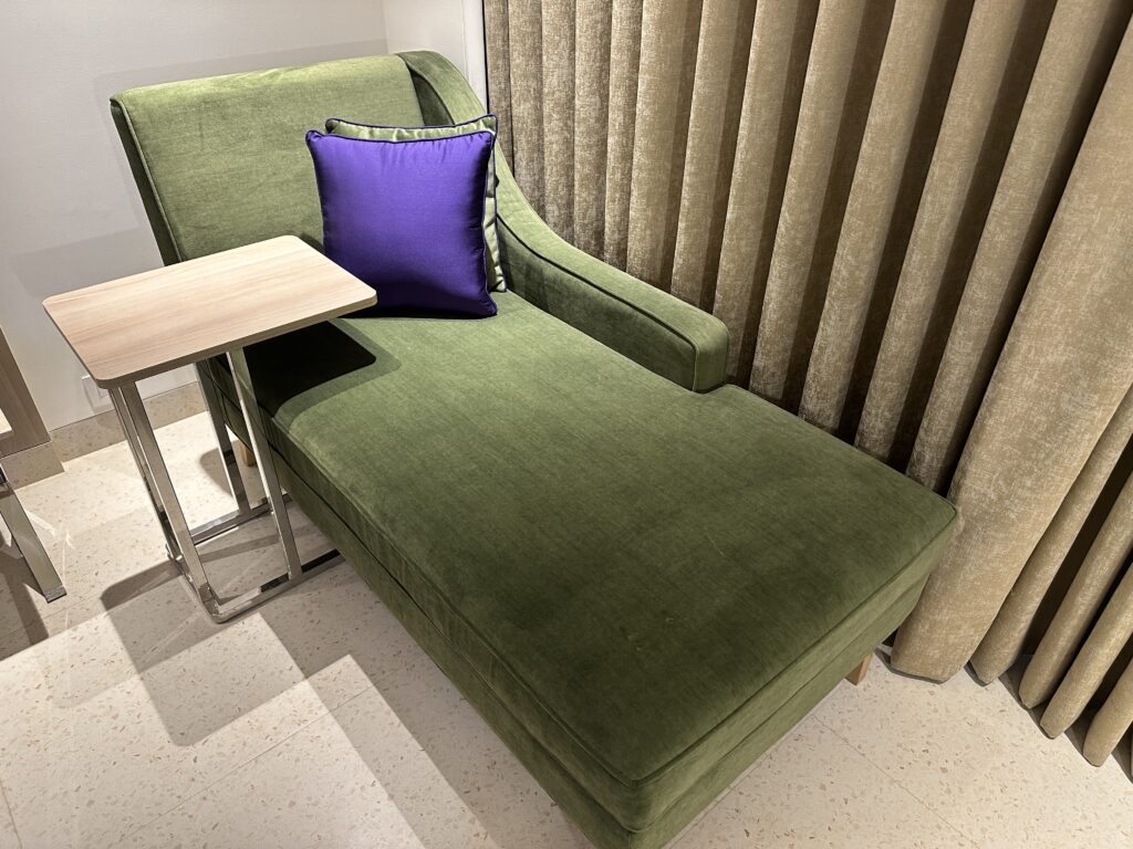 a green chaise lounge with a purple pillow next to a table