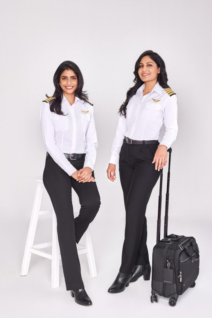two women in uniform standing next to a suitcase