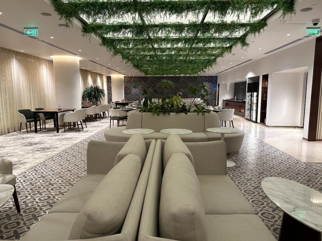 a room with white couches and tables and plants from ceiling