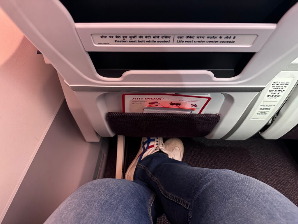 a person's legs in jeans and sneakers on an airplane