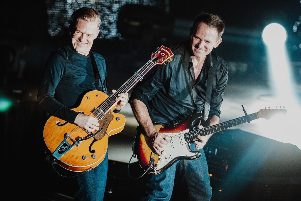 two men playing guitars on stage